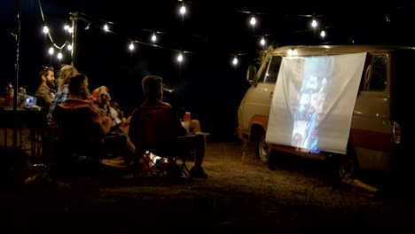 friends watching movie in campsite