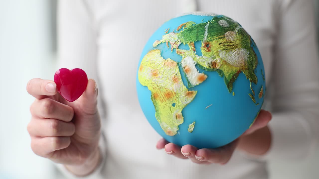 Person holding a globe and a red heart, symbolizing global love and environmental care
