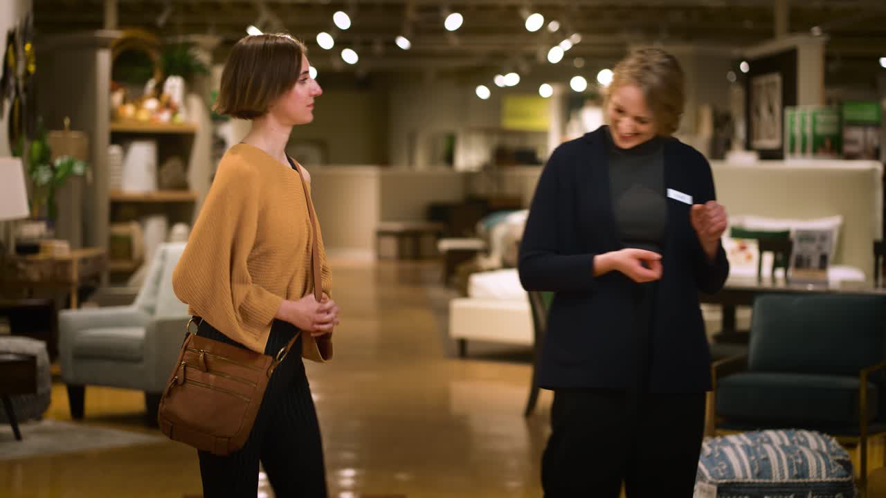 A Happy Sales Person Leads a Young Female Customer Into a Store