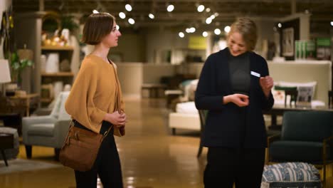a happy sales person leads a young female customer into a store