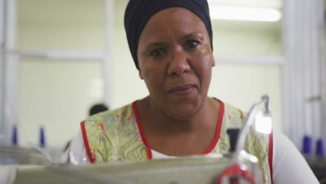 close up view of woman using sewing machine in factory