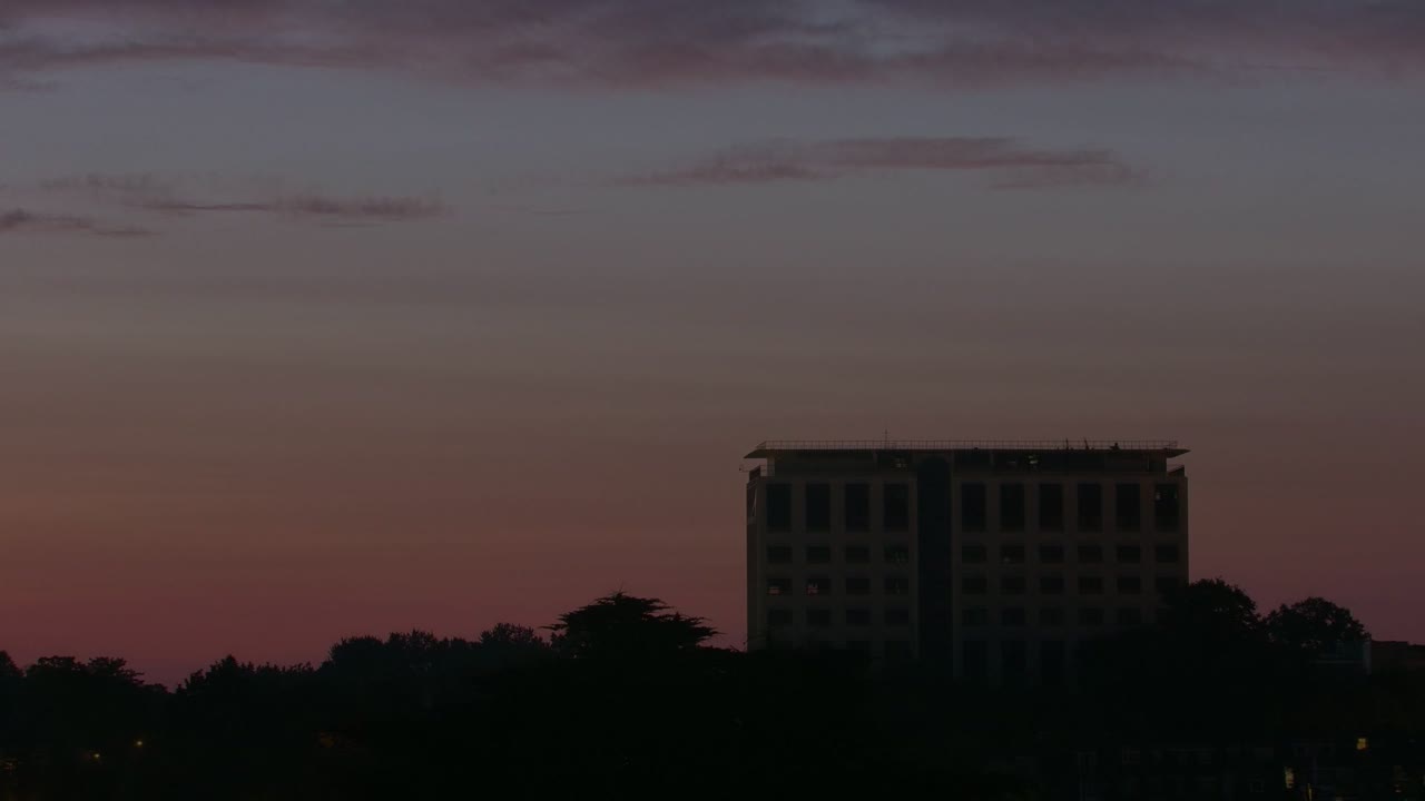 아래에 나무가 있는 높은 건물의 빠른 황혼에서 새벽 시간 경과