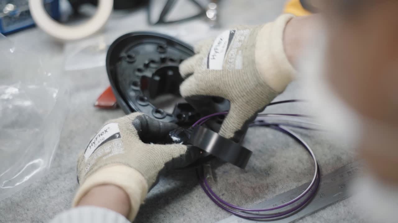 Closeup shot of a worker using electrical PVC table to wrap round cables which are installed in a metal part.