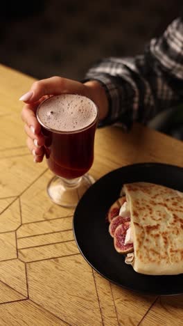 woman enjoying a warm drink and a fig and cheese pita sandwich