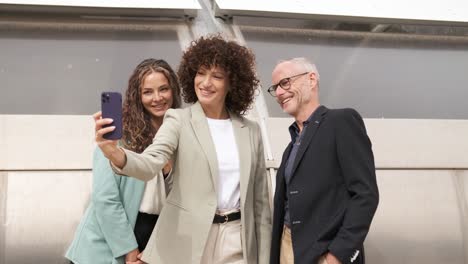 happy businesswoman taking selfie with coworkers in city