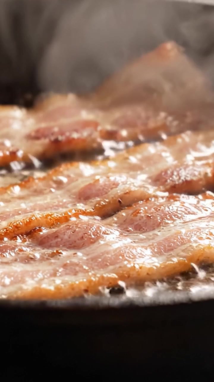 Pancetta Sfrigolante in Padella: Primo Piano Accattivante di Strisce Croccanti che Friggono nell'Olio Caldo, Emettendo un Aroma Irresistibile e un Magnifico Colore Dorato