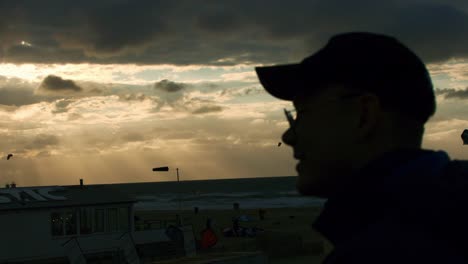 man with cap walks towards scheveningen beach during sunset, in 1000fps super slowmotion