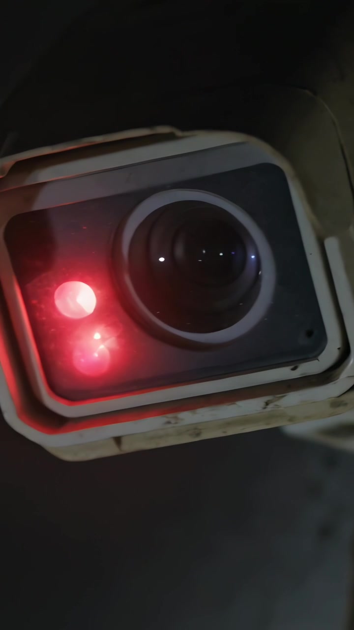 Video verticale: Inquadratura che si allontana rivelando l'obiettivo di una telecamera, diodi rossi e una base di montaggio a parete.