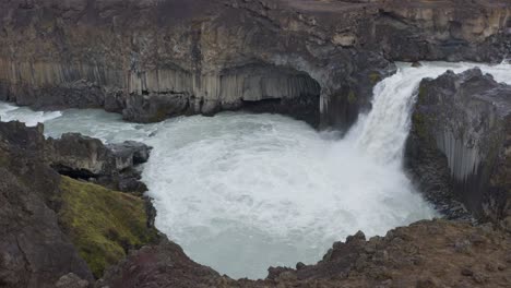 aerial top down shot of falling aldeyjarfoss waterfall in iceland - descending shot