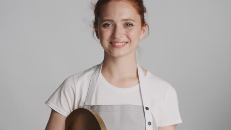 Redheaded-waitress-in-front-of-camera-on-gray-background.