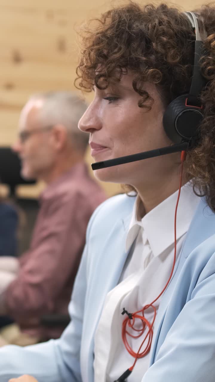 Forretningskvinne engasjert i en profesjonell samtale mens hun bruker et headset. Vertikal filmopptak