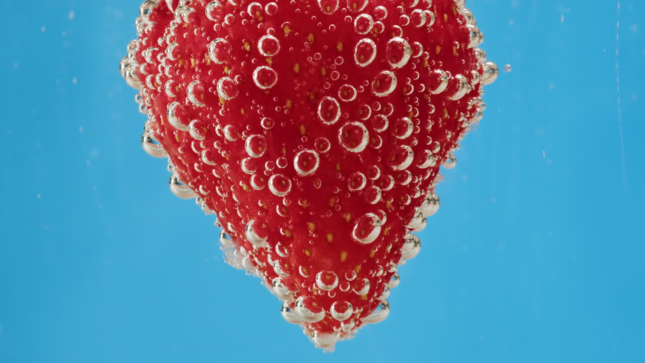 Strawberry submerged in water with bubbles