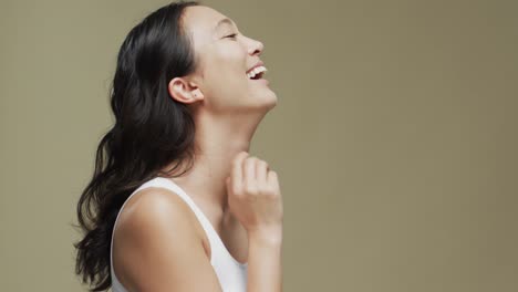 Feliz-Mujer-Asiática-Con-Cabello-Oscuro-Sobre-Fondo-Beige-Con-Espacio-Para-Copiar,-Cámara-Lenta