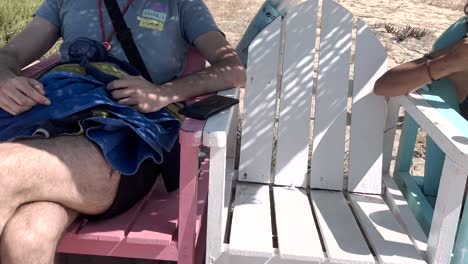 mujer rubia tomando el sol con su amigo en la playa y comiendo un helado en la playa de caparica