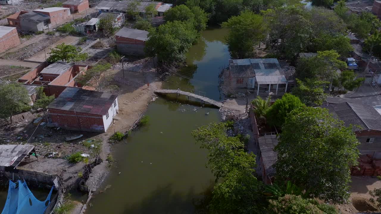Aerial drone shot over poor neighborhood in Cartagena and a child crosses the bridge