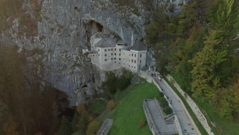disparo aéreo en cámara lenta con movimiento hacia adelante en el castillo de predjama al atardecer