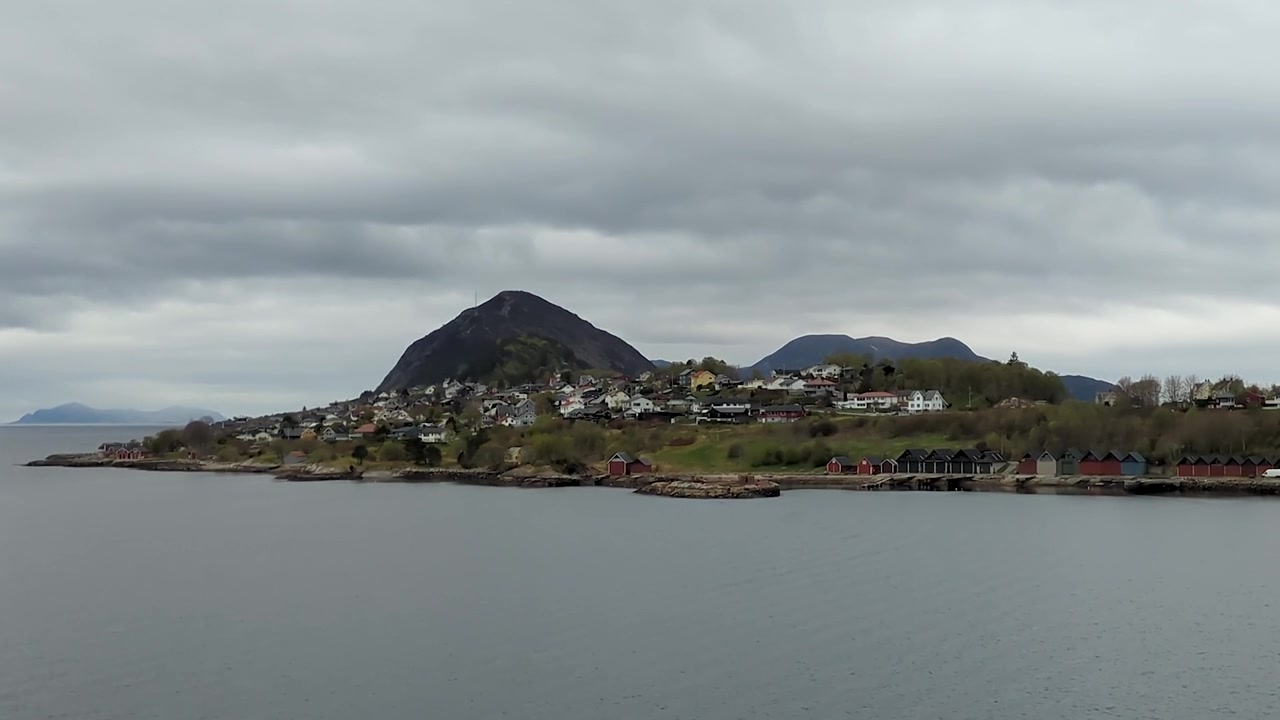Ålesunds havnefront med traditionelle bådhuse, huse på bjergsiden og snedækkede bjerge, Norge