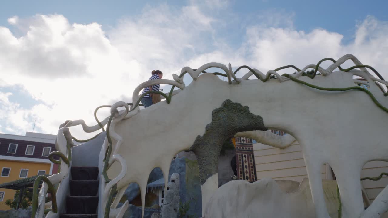 30대 젊은 여성이 베트남 달랏의 미친 집 계단을 오르고 카메라는 그녀를 따라간다.