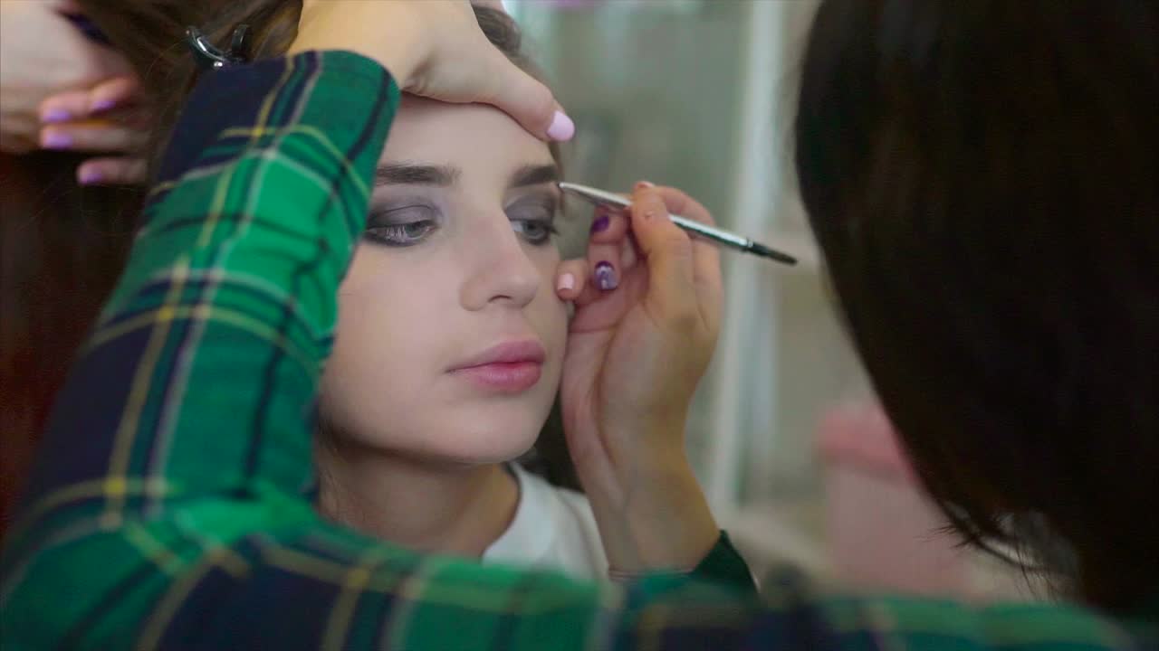 artista de maquillaje aplicando maquillaje a una mujer joven
