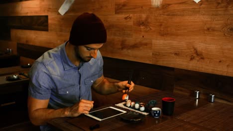 hombre usando tableta digital mientras tiene sushi