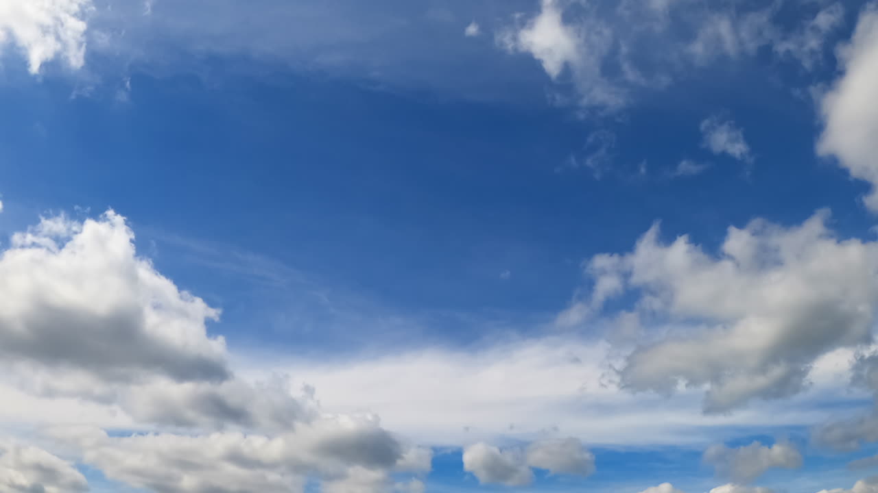 Blue sky with white clouds. Low angle view on the cloudscape lit by the bright sun. Timelapse.
