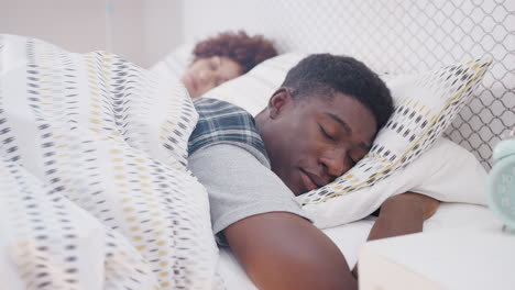 una pareja joven durmiendo en la cama en casa juntos.