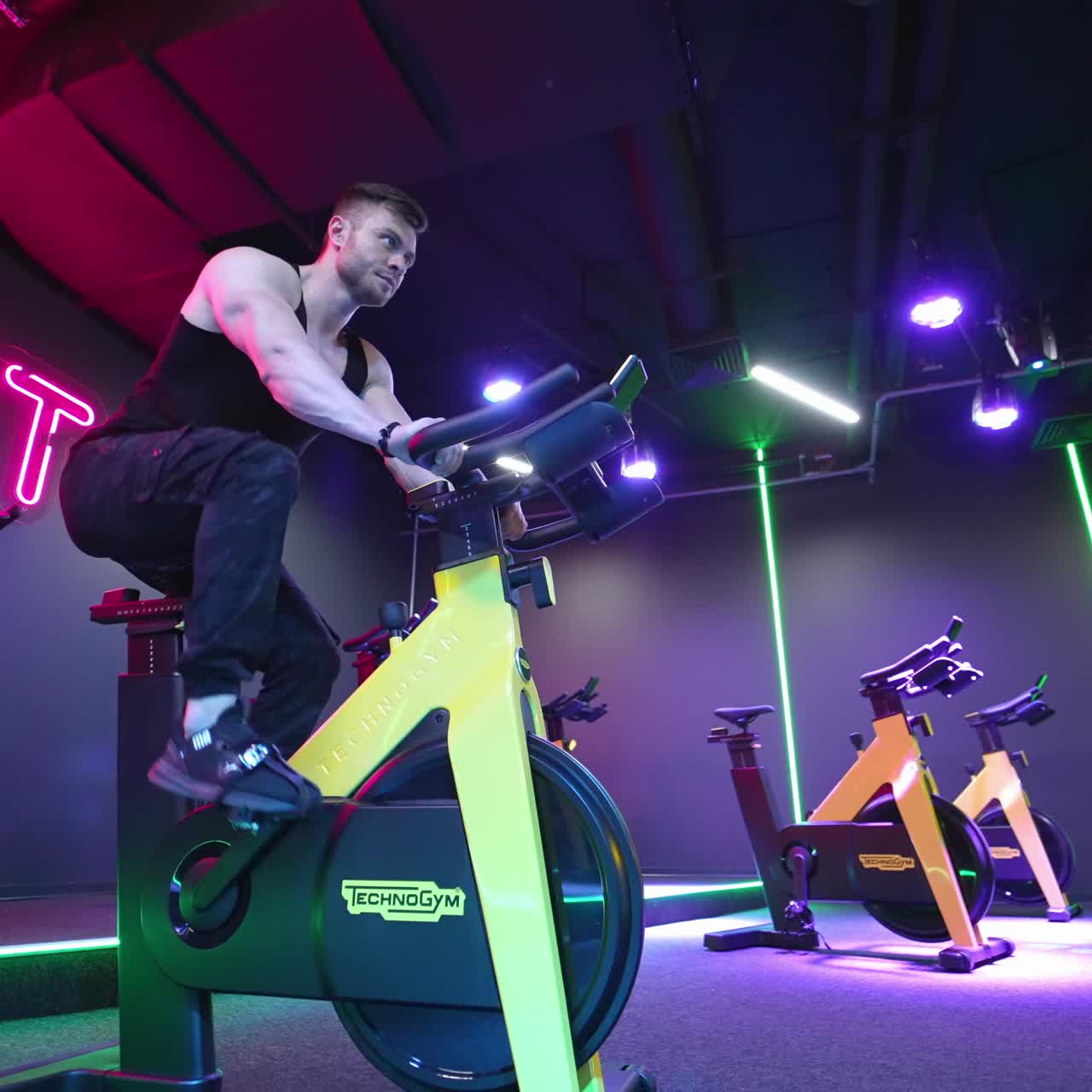 Man riding bike at gym. Handsome strong muscle man in gym doing cardio on bike