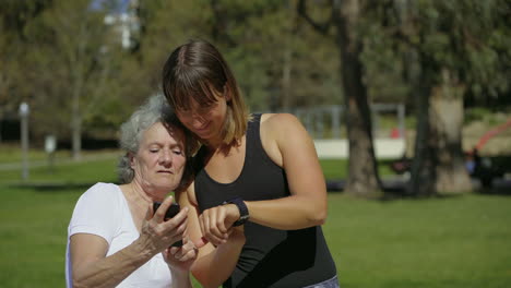 dos mujeres deportivas con dispositivos modernos en el parque de verano.