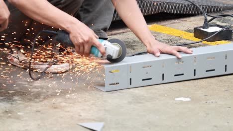 worker using grinder to cut metal piece