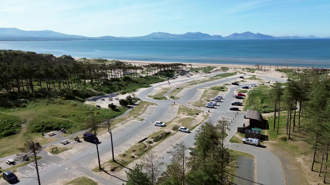 Newborough beach aerial view over sunny woodland car park coastline and Snowdonia mountain range