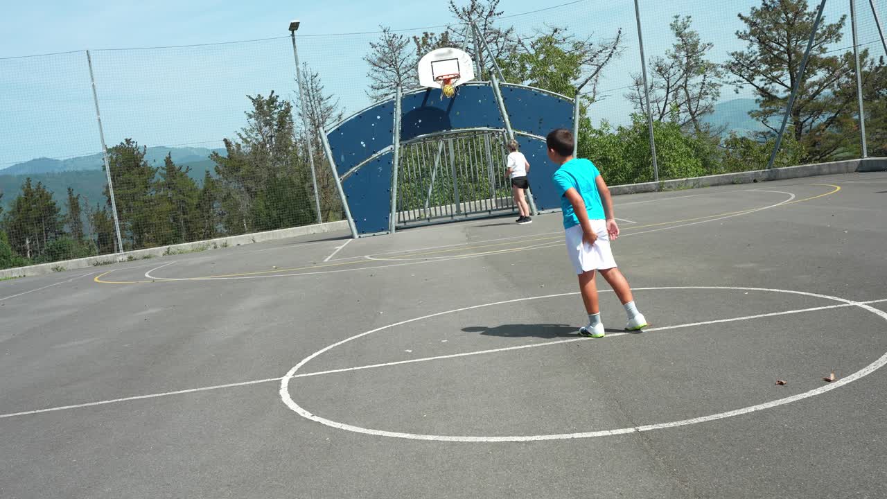 Donna e ragazzo giocano a basket in un campo all'aperto