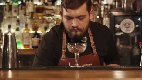 bartender pouring ice into a cocktail glass