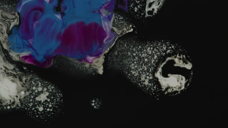 color purple, black, blue and white paint drops mixing in water