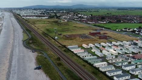 static caravan trailer beachfront staycation holiday home resort aerial rising view down beach railway