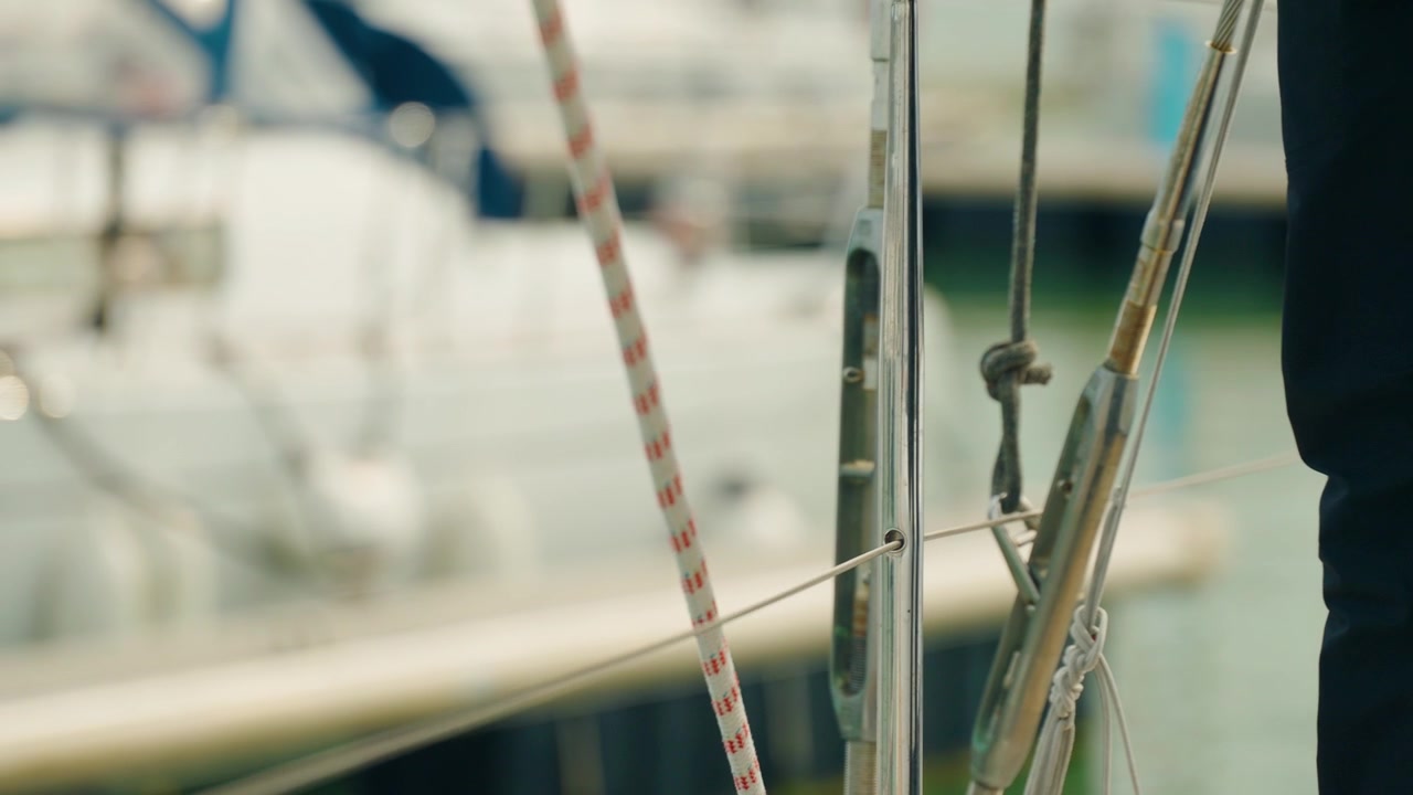 Gros plan au ralenti d'une amarre relâchée, signalant le départ d'un voilier du port et le début de son voyage