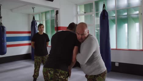 caucasian man learning self defense from trainer in gym