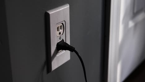 man removing two plugs from an at-home electrical outlet usa then opening and closing a closet door