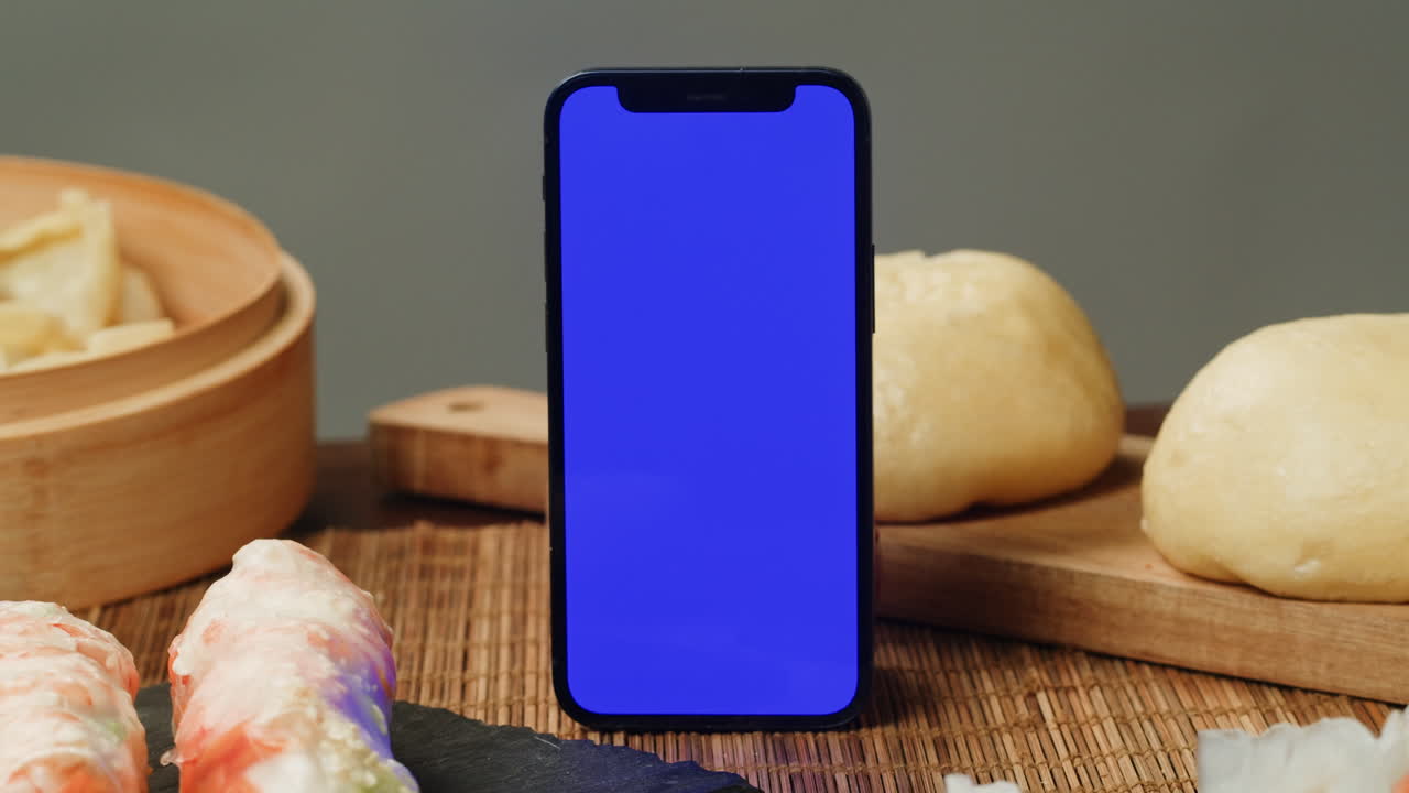 Smartphone with Blue Screen Mockup Surrounded by Asian Food