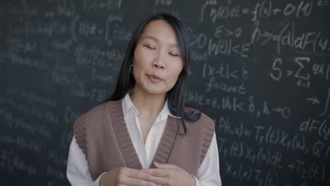 asian woman teacher explaining math on a blackboard