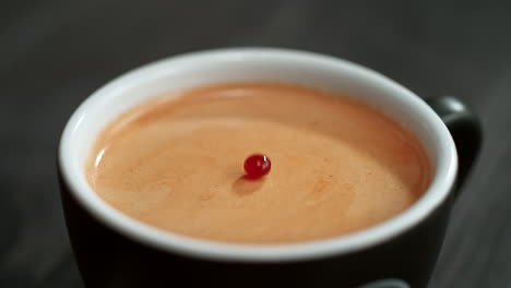 gotas de café cayendo y haciendo salpicaduras en una taza negra con crema de café, fondo oscuro