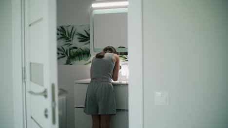 teenage girl washing face in bathroom