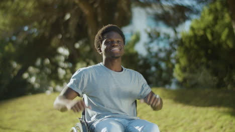 happy black guy in wheelchair raising arms and laughing