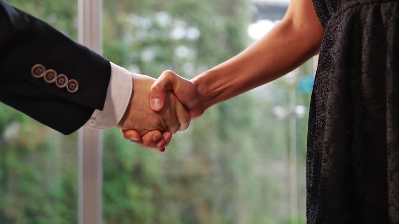 Business man and woman shaking hands in slow motion