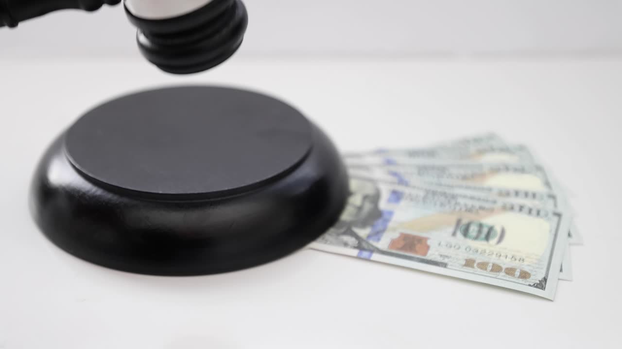 A Judge using a Wood Gavel and Sound Block with American Banknotes under.