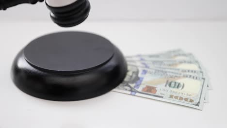 a judge using a wood gavel and sound block with american banknotes under.