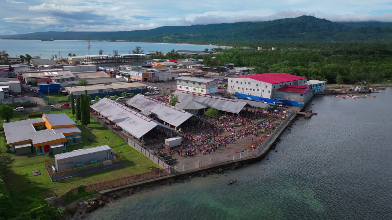 Sundaun fish Market Wewak Hill buildings traffic people Boram road Wewak Papua New Guinea aerial drone downtown coastal town Sundaun Market Dogreto Bay sunny blue sky morning circle right motion