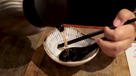 chopsticks and spoon with sauce in bowl