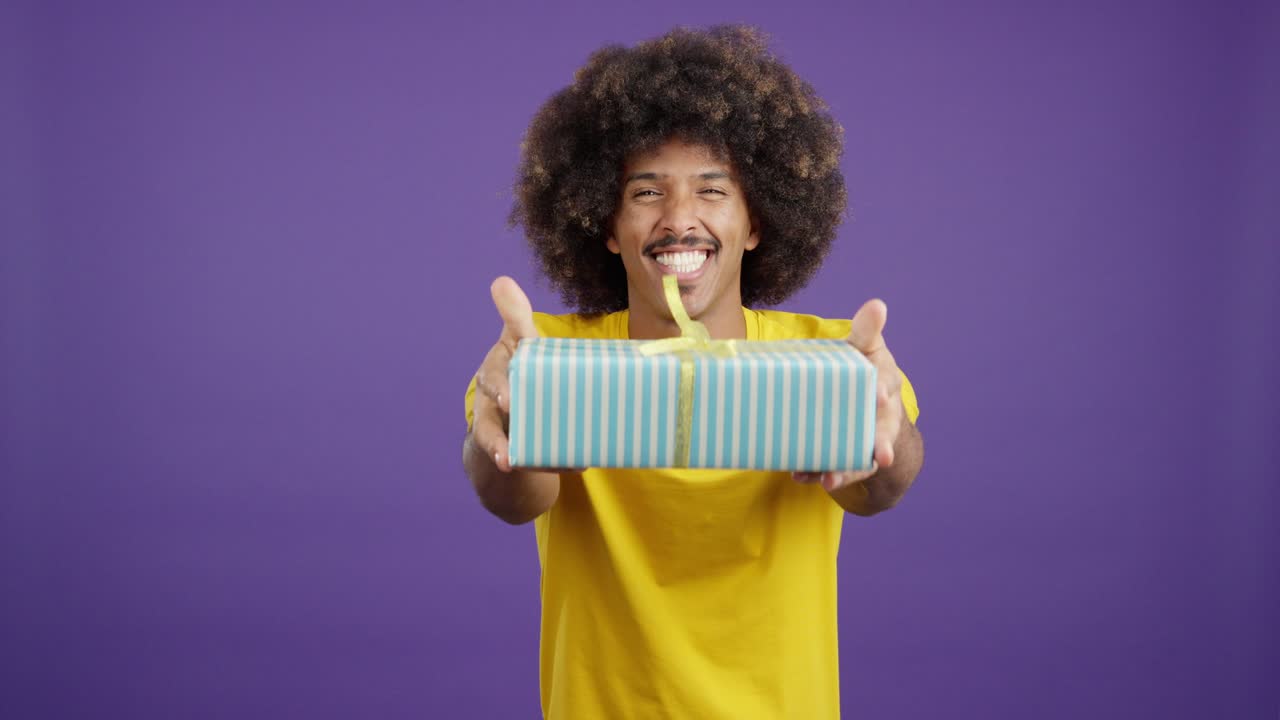 Happy man with afro hair smiles and offers a gift