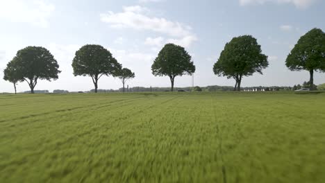 aerial pull-out shot showing cars driving past a meadow with tractor tracks through