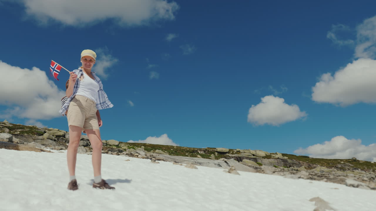 한 여자가 밖에 산에서 눈 위를 걷고 있습니다. 더운 여름입니다. 눈이 녹지 않았습니다.